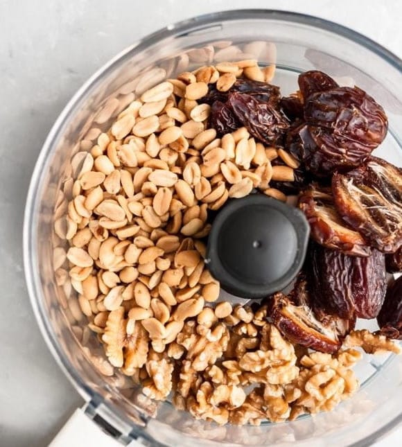 Nut and date base ingredients in a food processor: almonds, pistachios and dates ready to blend